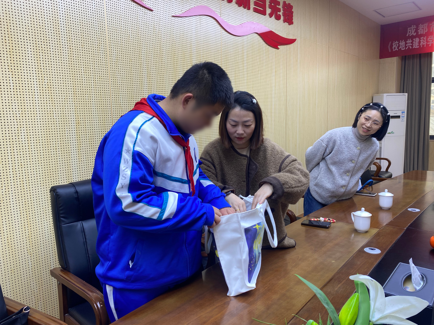 项目工作人员陪伴受助学生查看公益物资